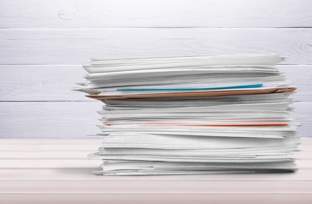 Stack of Assorted Papers on a White Desk Against a Light Wood Background — Lehmann Print Solutions in Bowen, QLD