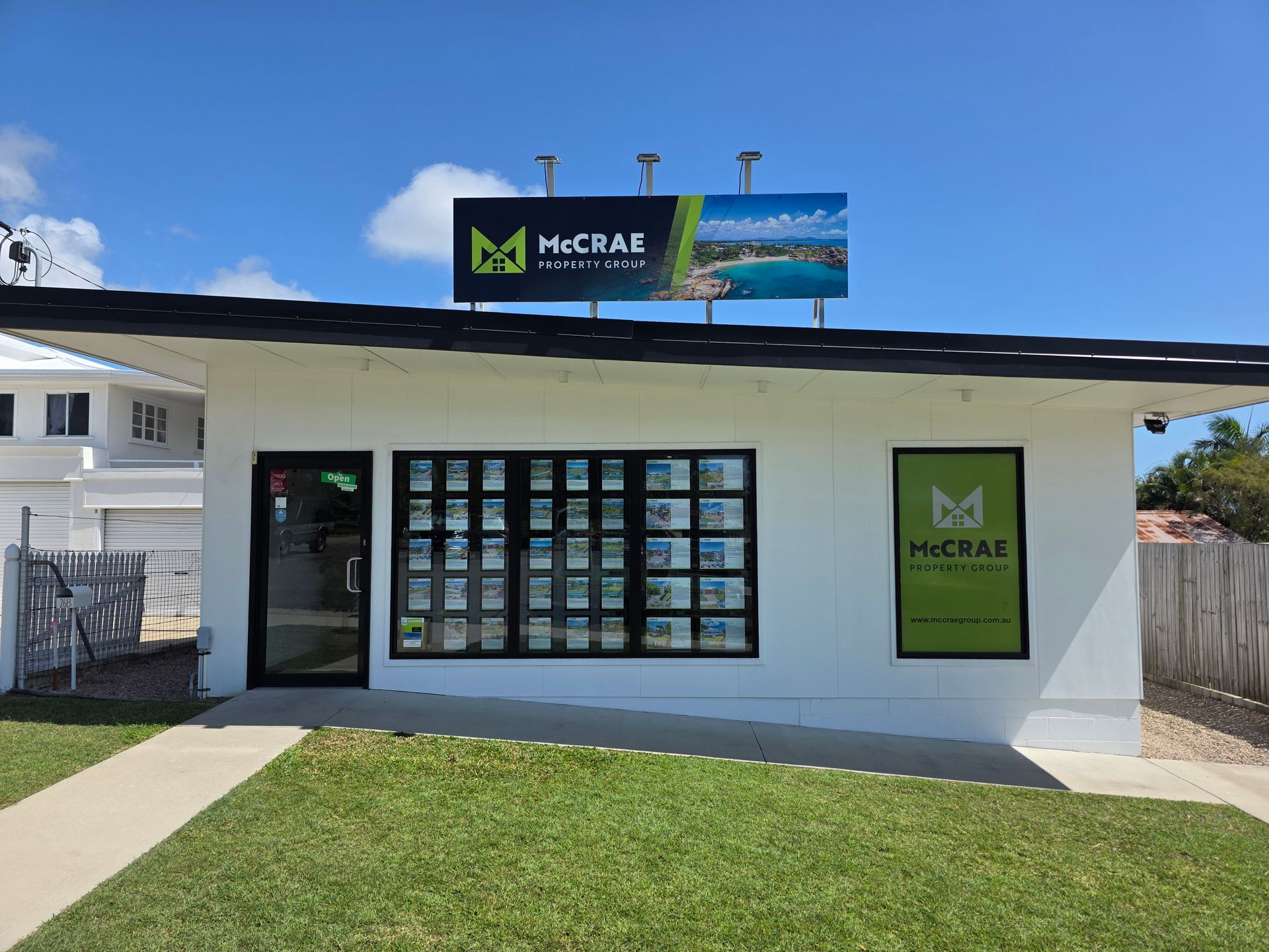 Small white storefront with a McCray sign, large front window, and grassy lawn under a blue sky. — Lehmann Print Solutions in Bowen, QLD