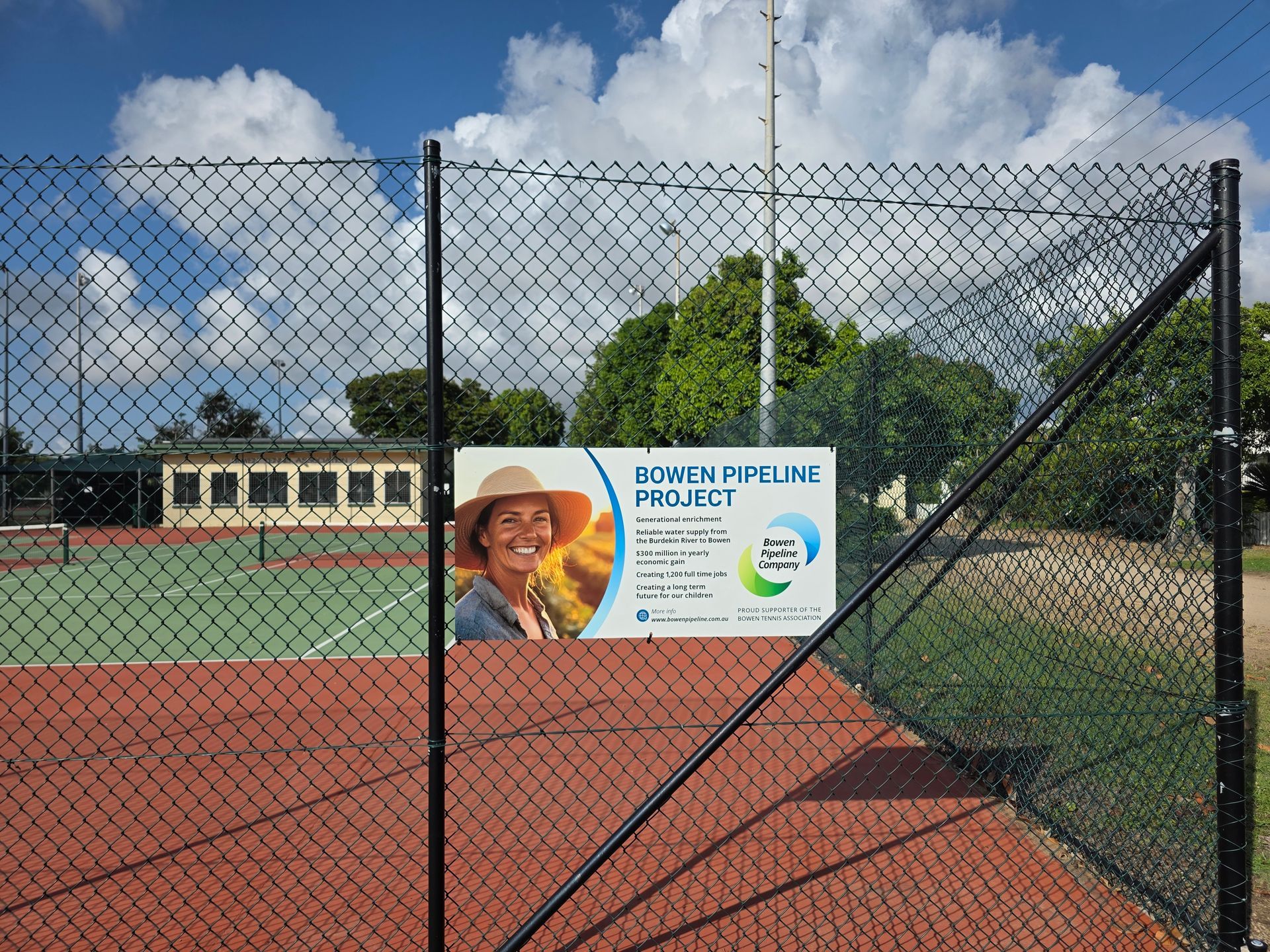 Chain-link Fence With a Blue Sign Beside a Red Tennis Court — Lehmann Print Solutions in Bowen, QLD