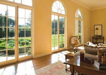 Bright living room with large arched windows, sunlit hardwood floors, and a view of green gardens outside — Lehmann Print Solutions in Bowen, QLD