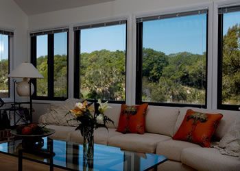 Bright living room with large windows, beige sofa, glass coffee table, and a view of green trees outside — Lehmann Print Solutions in Bowen, QLD