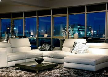 Modern living room with white sectional sofa, black coffee table, and city lights at night through large windows — Lehmann Print Solutions in Bowen, QLD