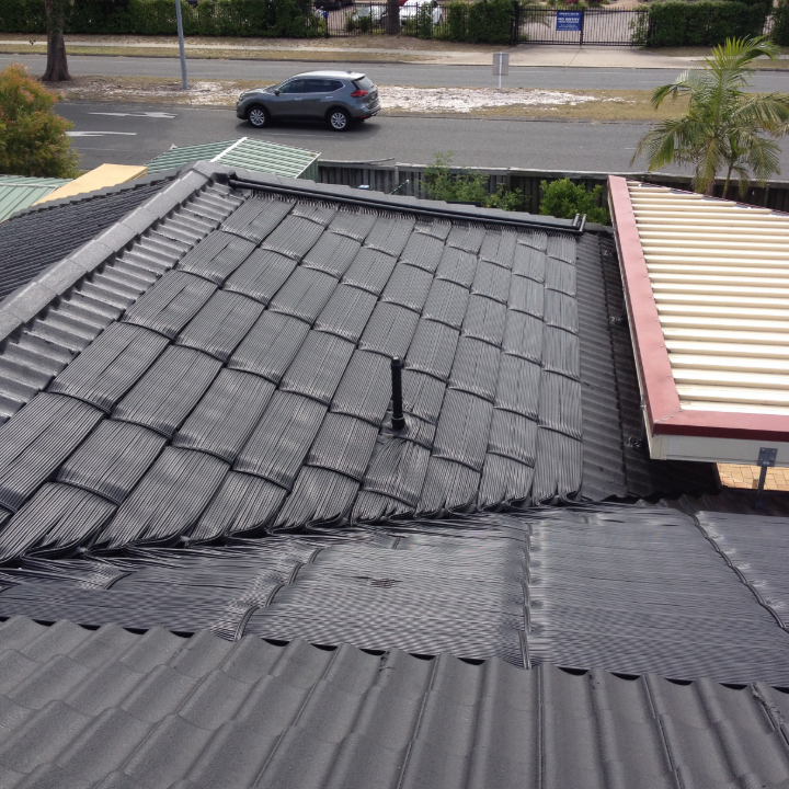 A Car is Driving Down a Street Next to a Roof — Newcastle Solar Pool Heating Systems In Wyong, NSW