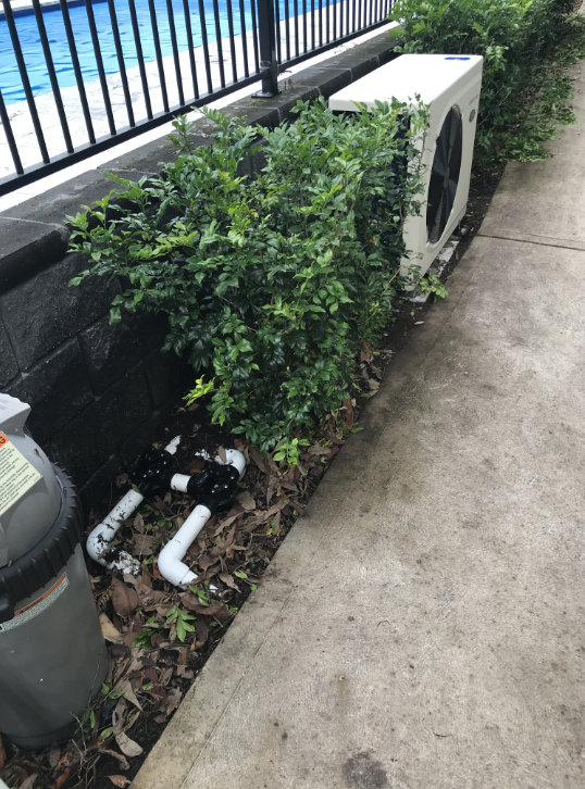 A White Air Conditioner is Sitting on the Sidewalk— Newcastle Solar Pool Heating Systems In Lake Macquarie, NSW