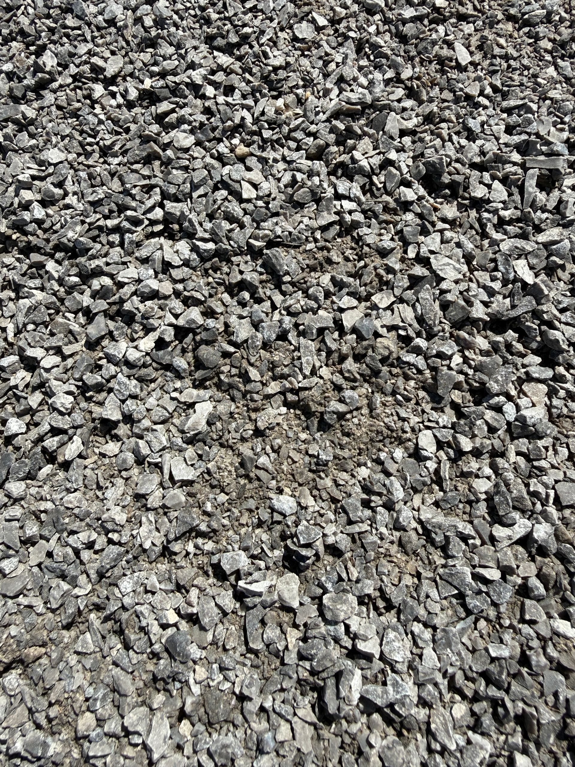 Close-up of gray gravel stones covering the ground, with a lighter patch in the center
