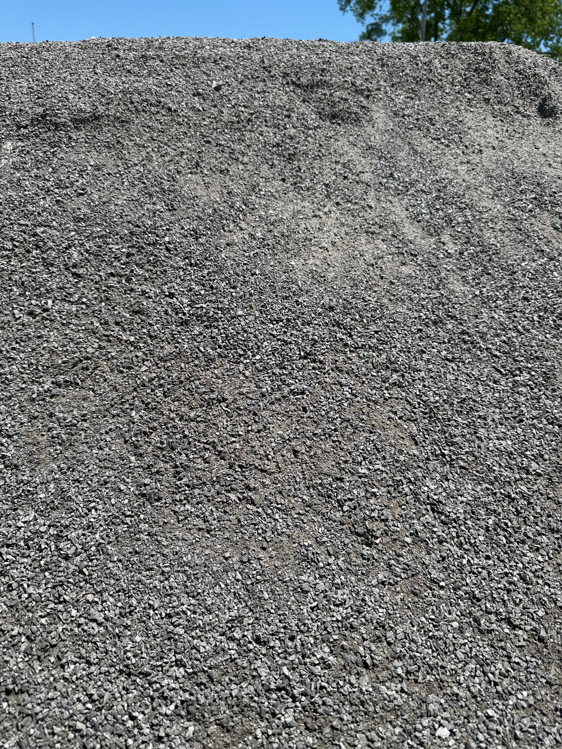A large pile of gray gravel under a clear blue sky
