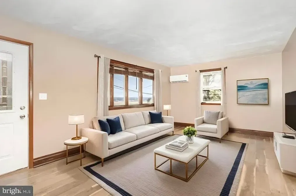 Bright living room with beige sofa, armchair, coffee table, and window light