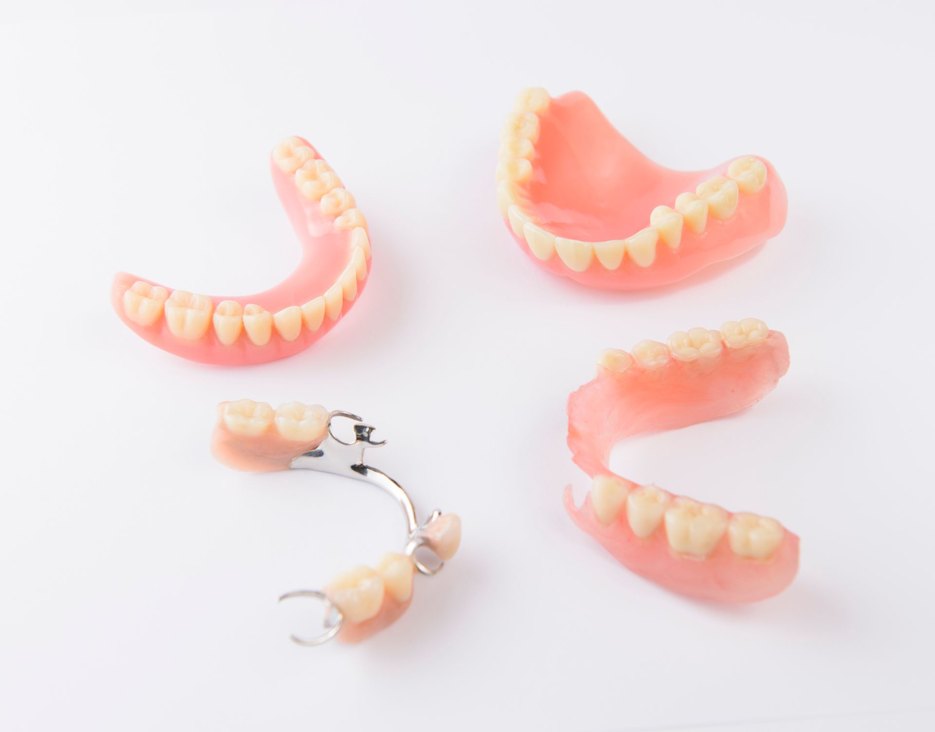 A group of dentures are sitting on top of each other on a white surface.