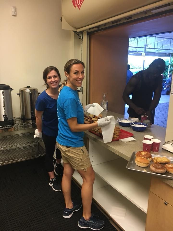 a woman in a blue shirt is standing next to another woman in a kitchen .