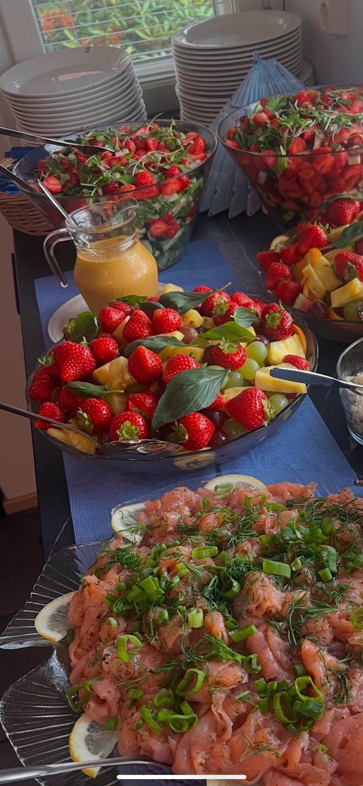 Pöydällä erilaisia hedelmäkuorrutteisia jälkiruokia ja yksi suolainen annos, taustalla pinottuja lautasia
