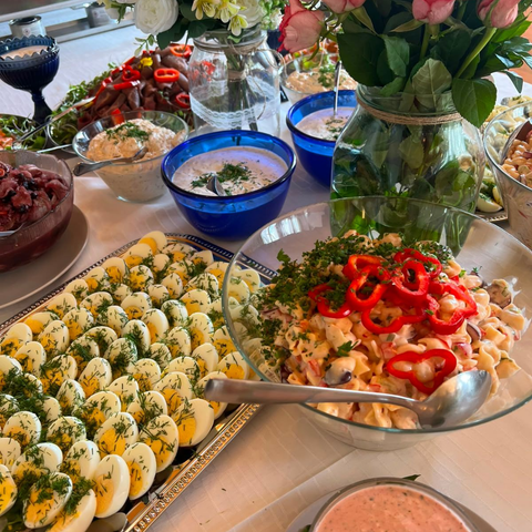 Buffetpöytä, jossa on paholaisenmunia, salaattikulhoja ja kukka-asetelmia, joiden päällä on chilirenkaita.