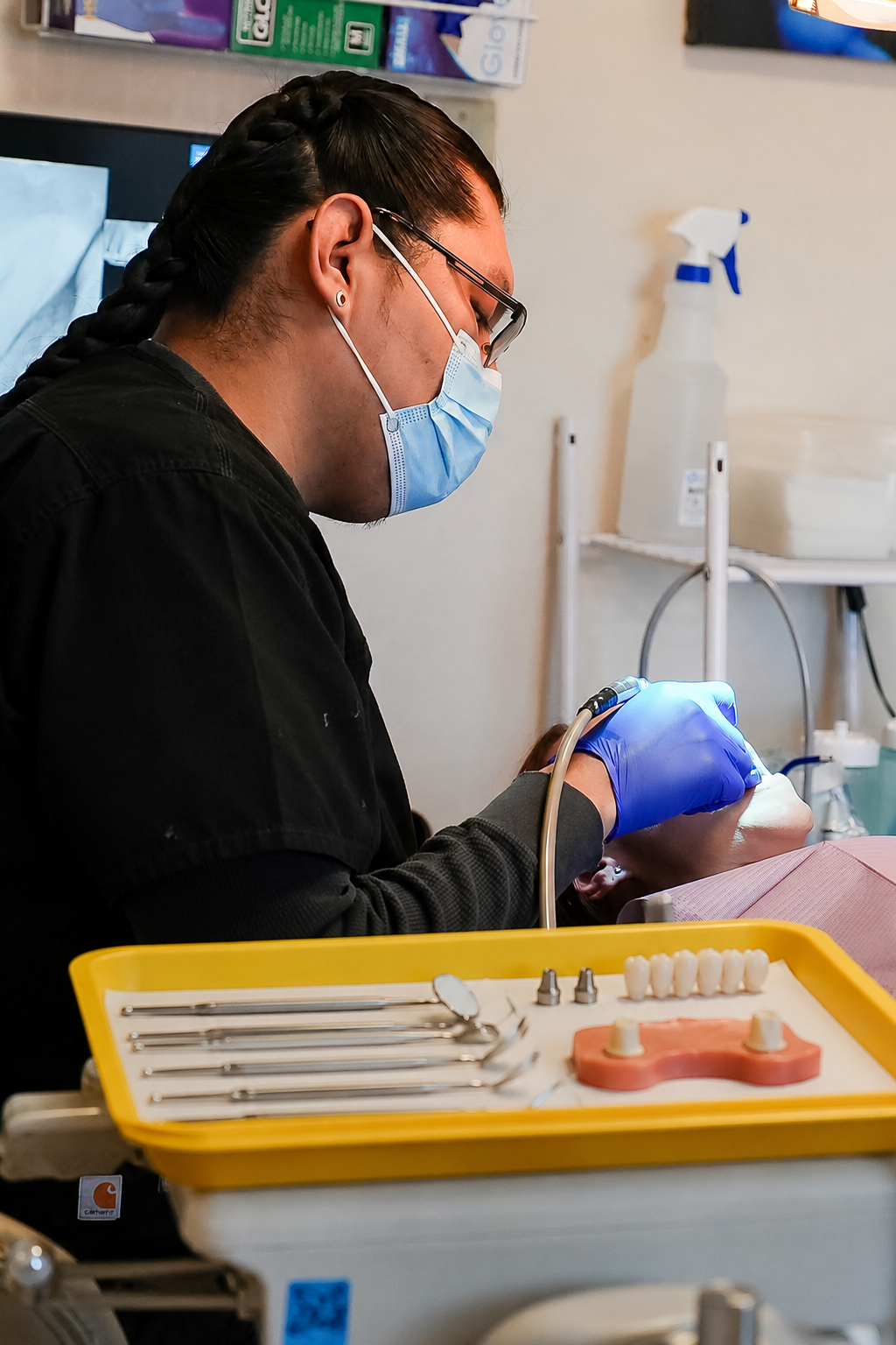 Dentist in blue gloves working on a patient’s teeth in a clinic, with dental tools in the foreground