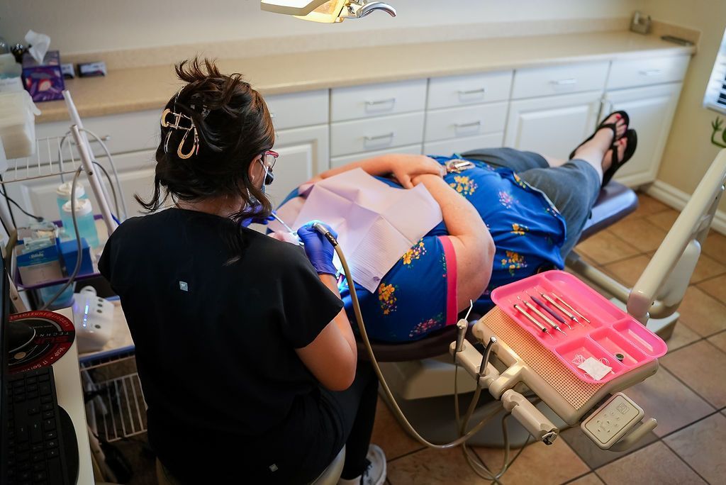 Person receives a medical treatment in a clinic, with a caregiver beside them and supplies on a tray.