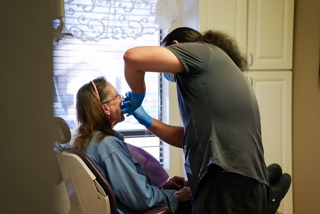Dentist examining a seated patient in a clinic