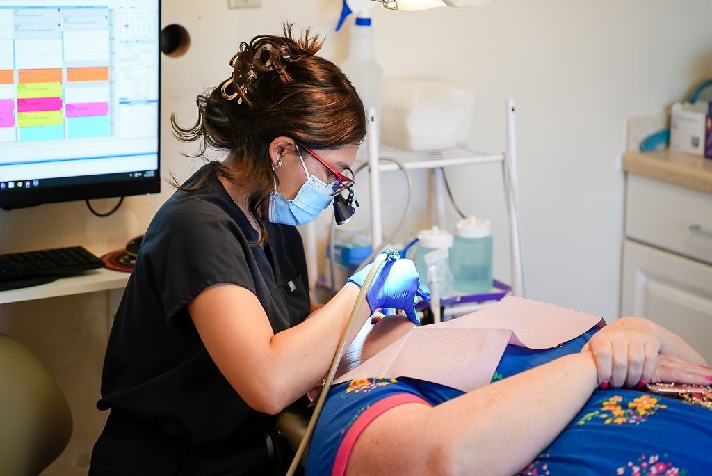Dentist using a tool to treat a patient reclining in a clinic chair