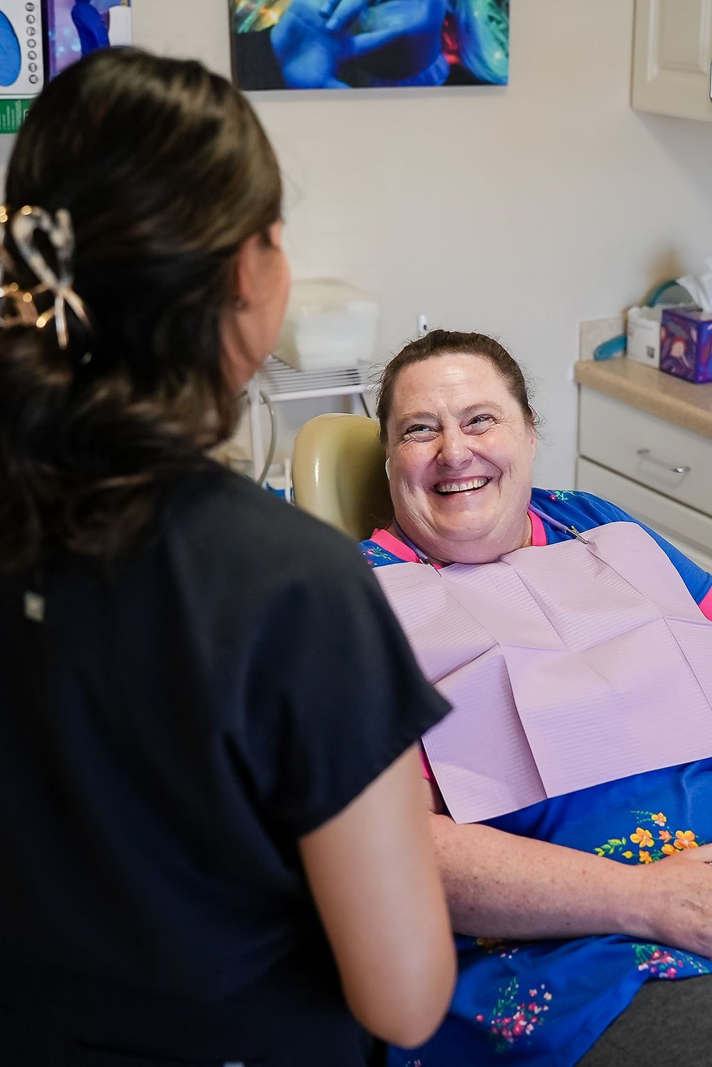 Patient smiling in a dental chair while a clinician stands nearby