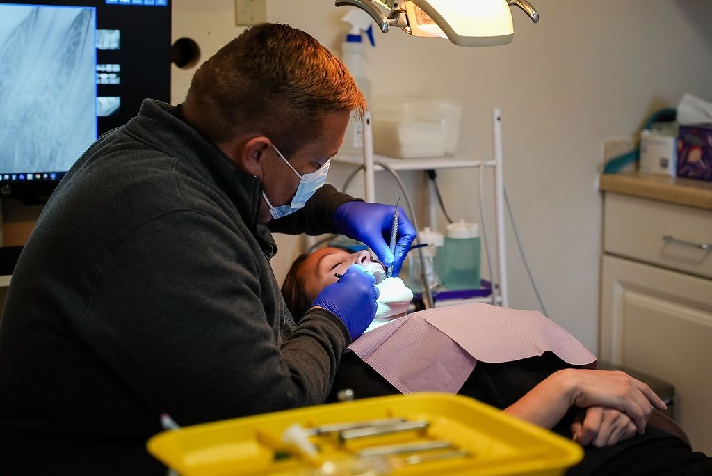 Dentist wearing a mask and gloves works on a patient in a dental clinic