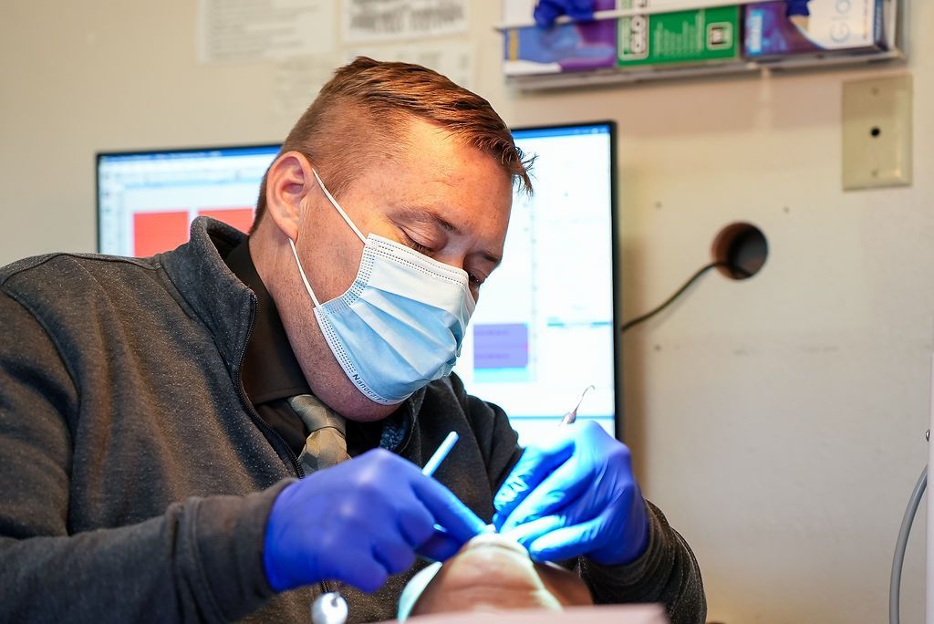 Dentist working on a patient’s teeth under a bright exam lamp in a clinic office