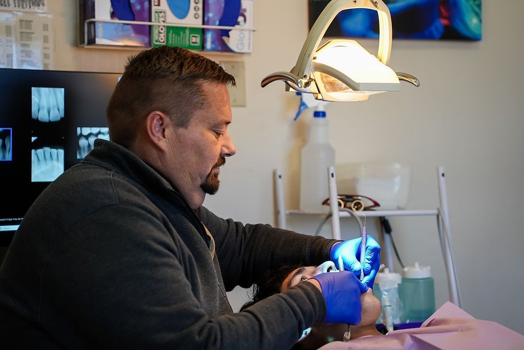 Dentist working on a patient's teeth under a bright exam lamp
