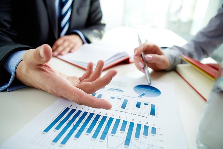A Man and a Woman Are Sitting at a Table Looking at a Graph — Peter Maundrell & Company Pty Ltd in Emerald, QLD