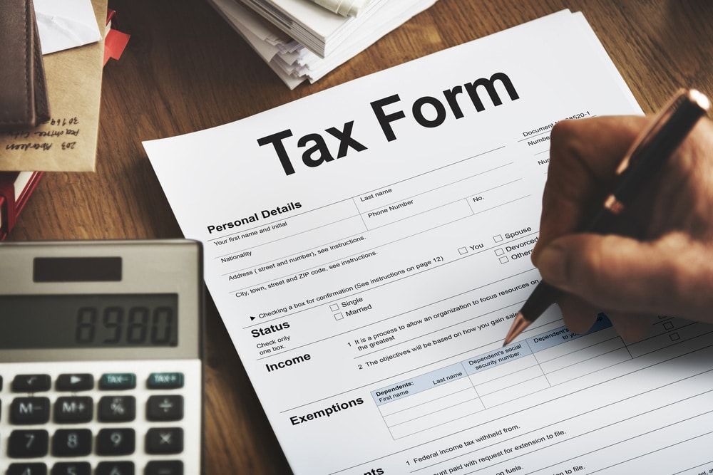 A Person is Filling Out a Tax Form Next to a Calculator — Peter Maundrell & Company Pty Ltd in Emerald, QLD