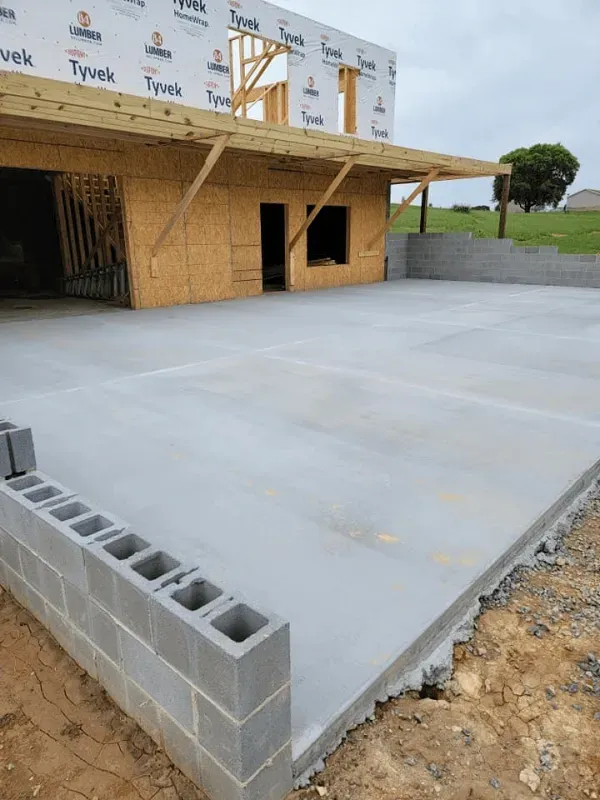 Concrete slab beside unfinished building with cinder blocks and plywood walls