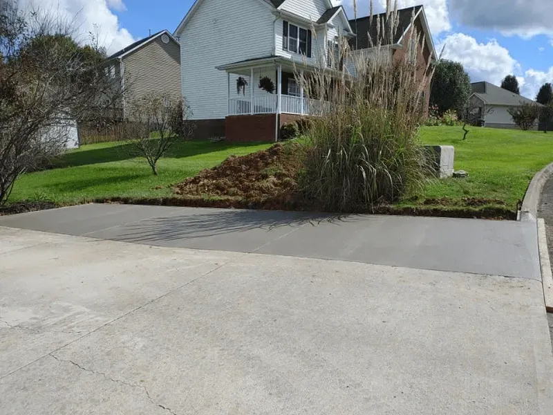 Suburban house with a sloped lawn, driveway, and ornamental grasses by the curb