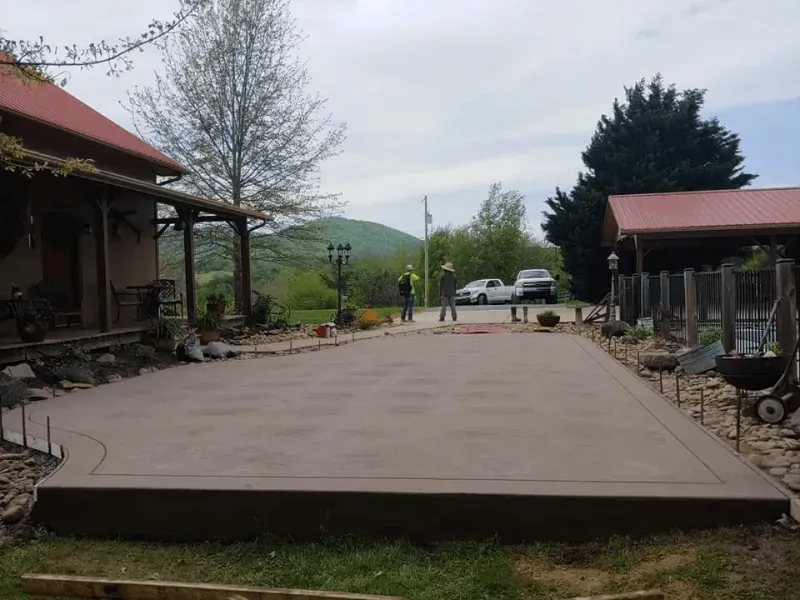 Outdoor concrete platform beside rustic buildings, with cars and people in a rural setting.