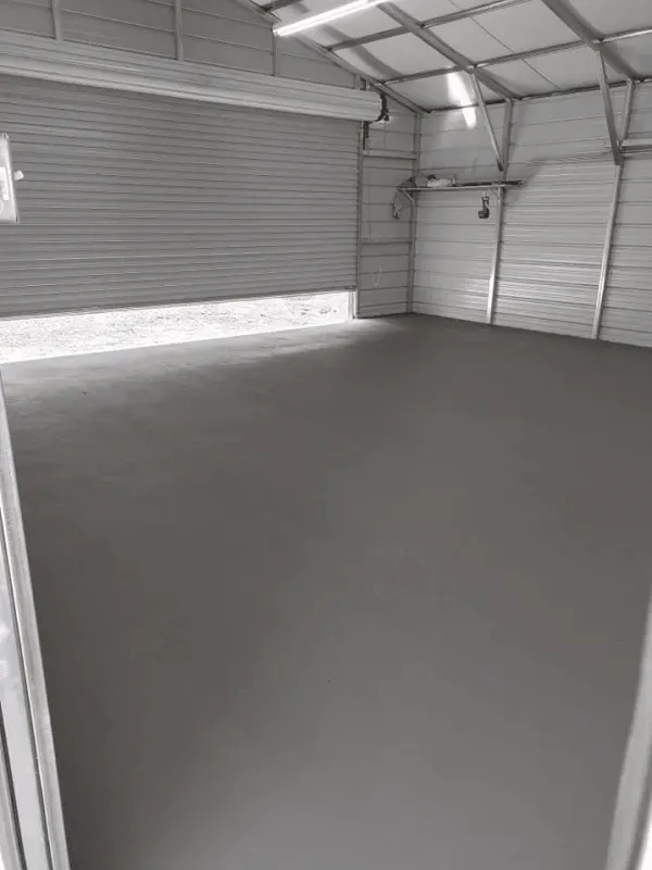 Empty metal garage with a gray concrete floor and closed roll-up door