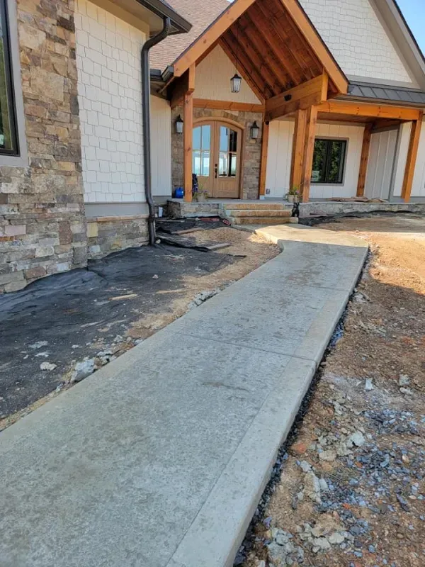 Concrete accessibility ramp leading to a stone house entrance under construction