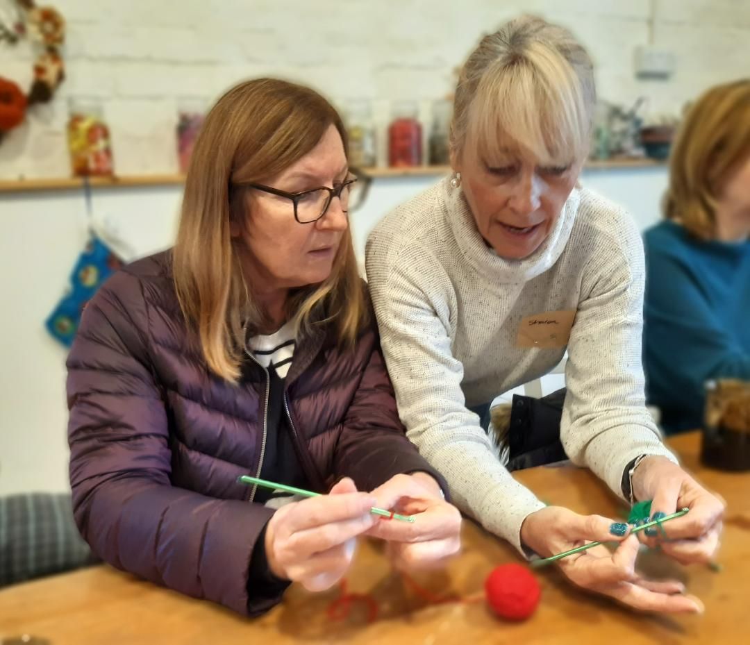 one lady showing another lady how to crochet