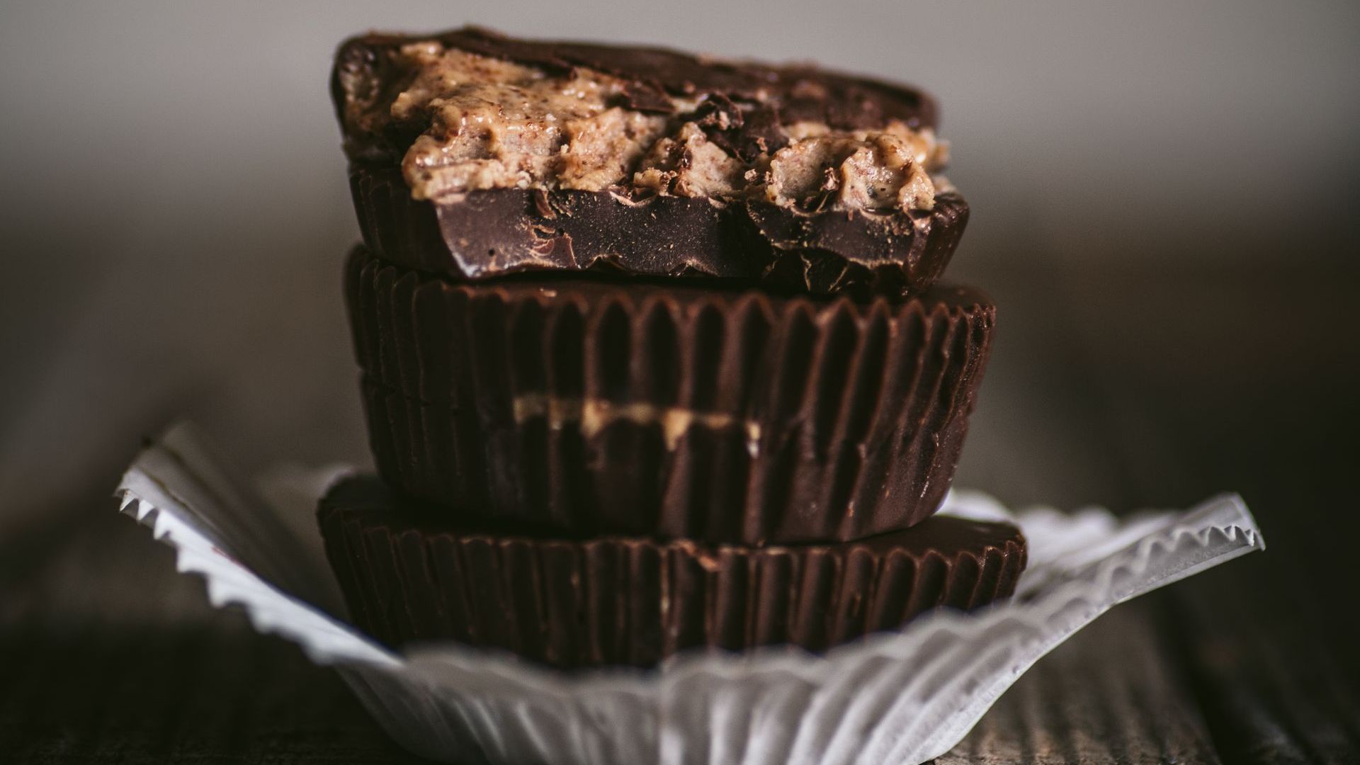 Two chocolate peanut butter cups are stacked on top of each other on a white plate.