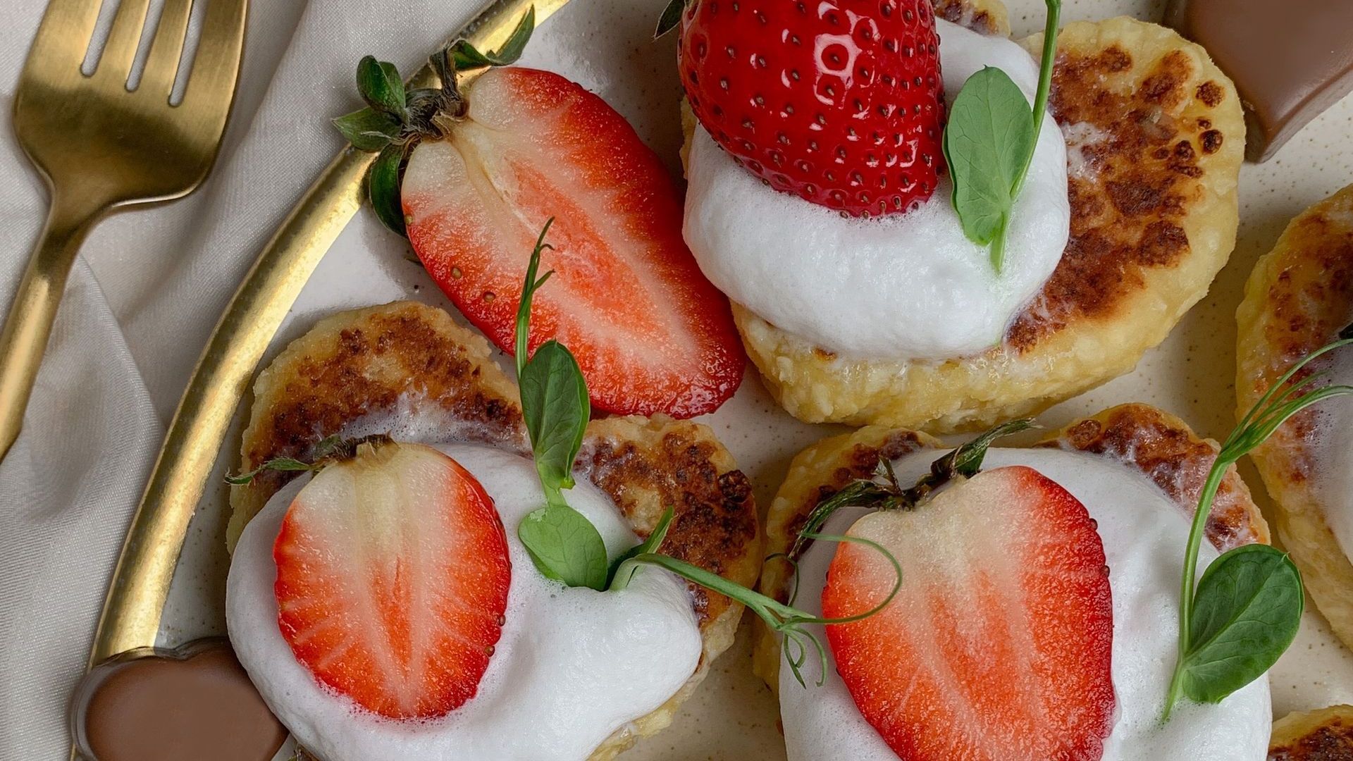 A close up of a plate of food with strawberries and whipped cream on top.