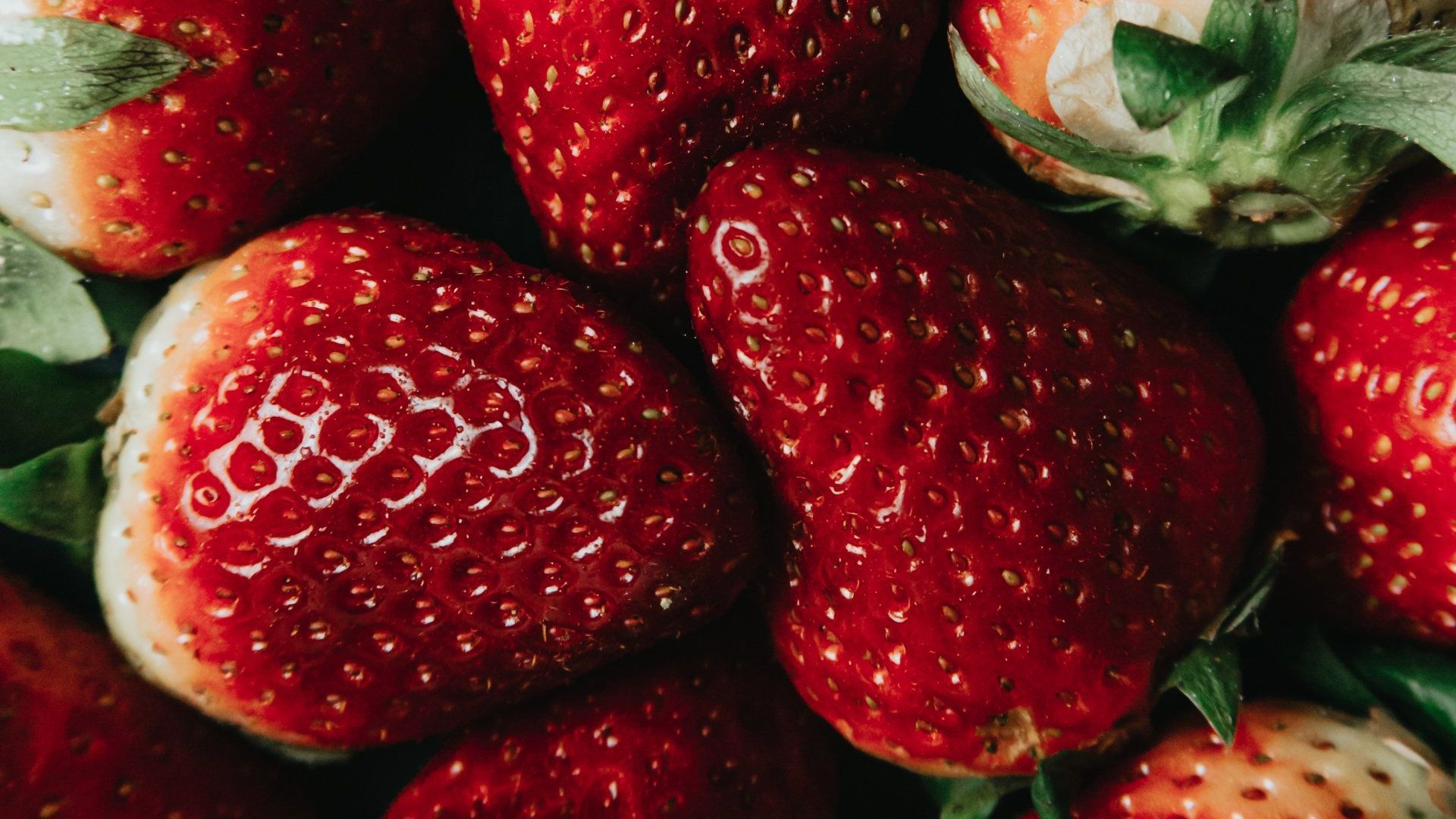 A bunch of strawberries are sitting on top of each other on a table.