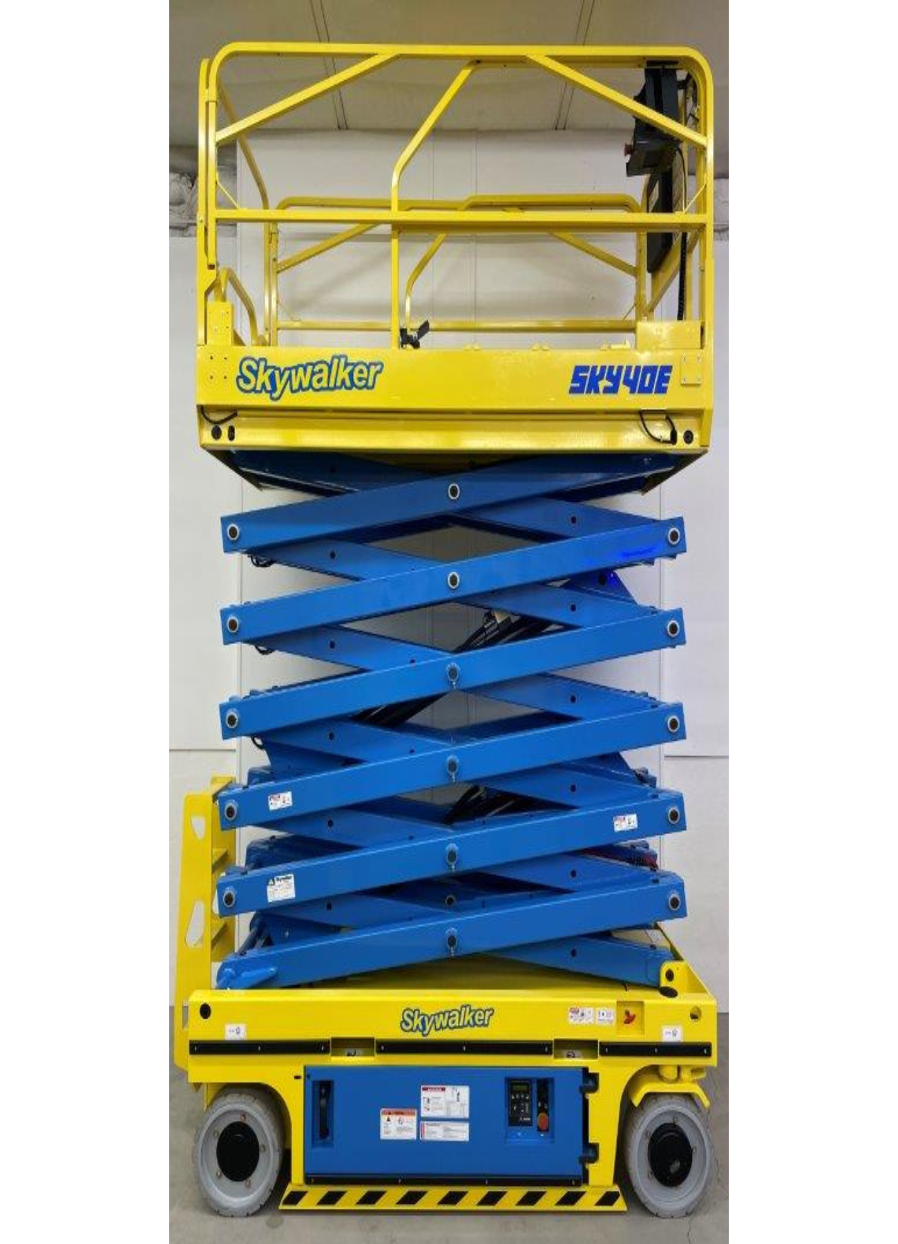 A blue and yellow scissor lift is sitting in a garage.