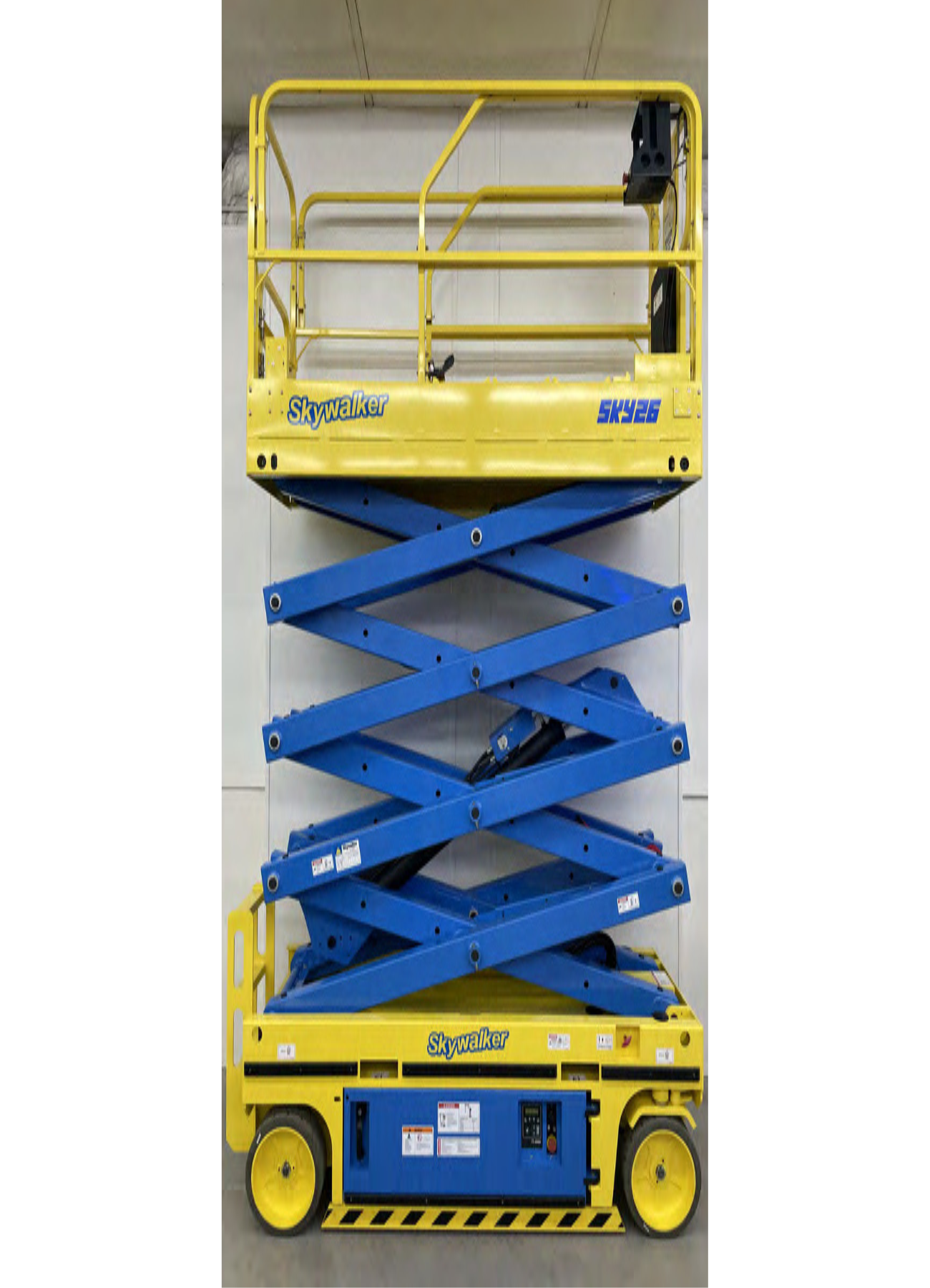 A yellow and blue scissor lift is sitting in front of a white wall.