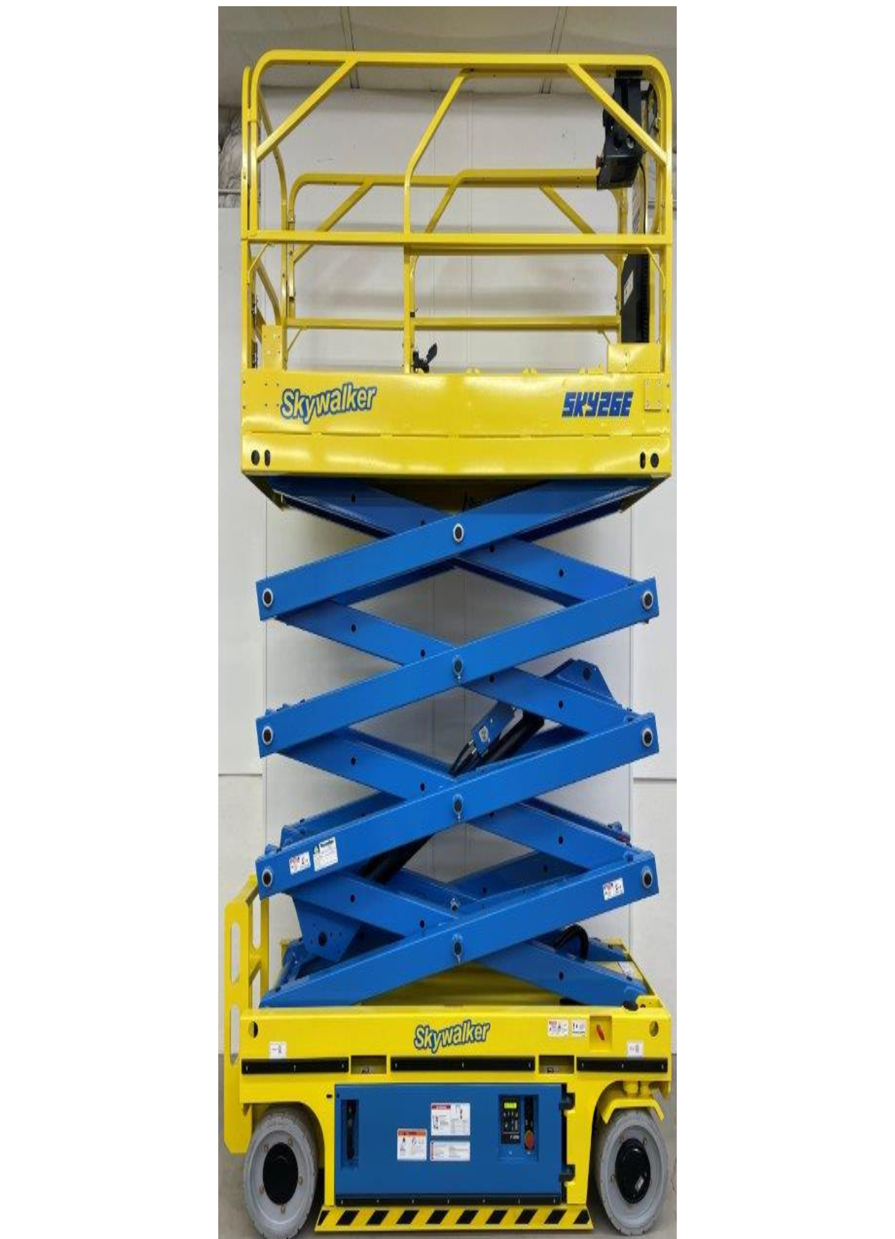A yellow and blue scissor lift is sitting on top of a white wall.