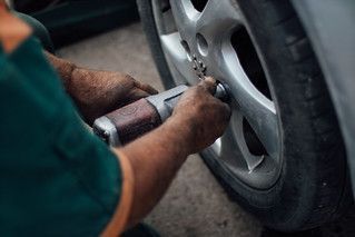 Mechanic using a pneumatic wrench to tighten a car wheel lug nut