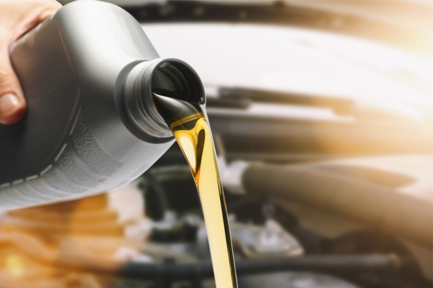 Pouring motor oil from a gray container into an engine