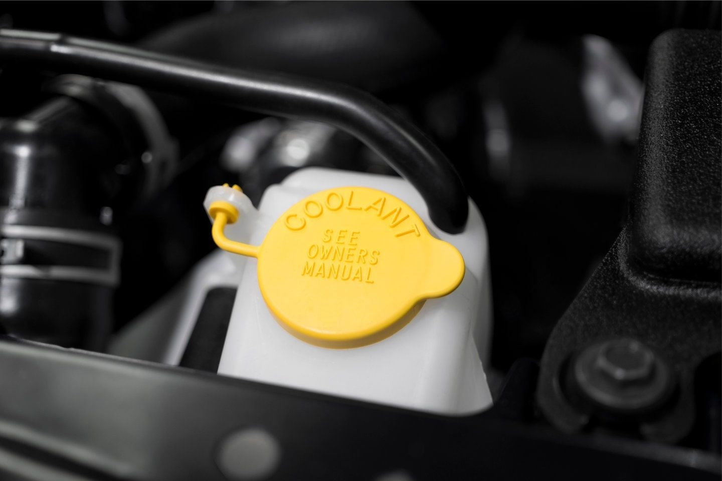 Yellow coolant reservoir cap in a car engine compartment