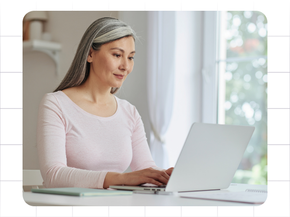 Woman typing on a laptop at a desk in a bright room
