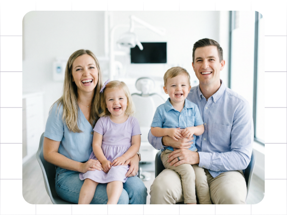 Smiling family of four seated together on a couch in a bright living room