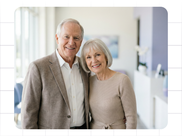Smiling couple standing together in a bright hallway, wearing beige and white sweaters