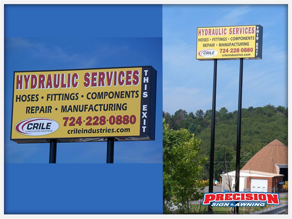 Two signs for Hydraulic Services. Yellow and black signs on poles, text includes phone number and website.