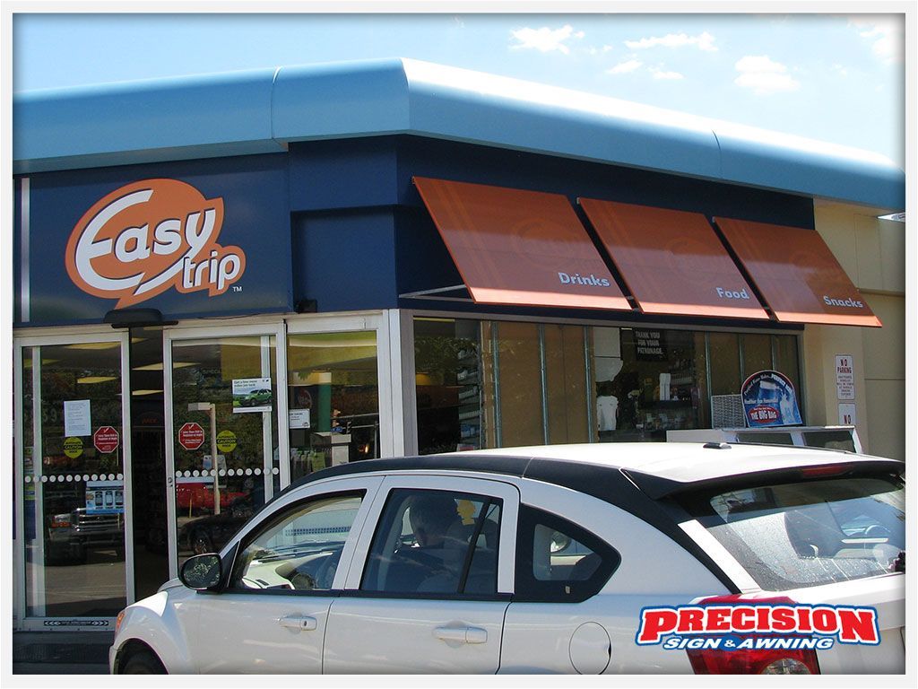 Easy Trip convenience store exterior with orange and blue signage, a white car parked in front.