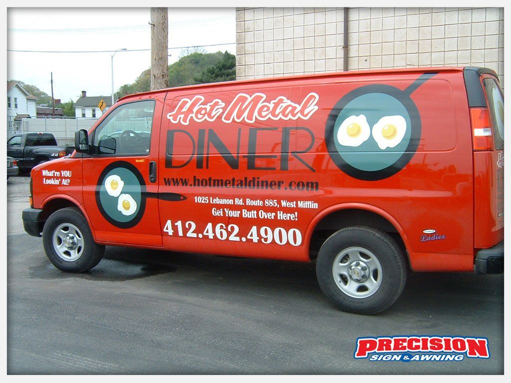 Red van with "Hot Metal Diner" logo, featuring fried eggs, parked on a street.