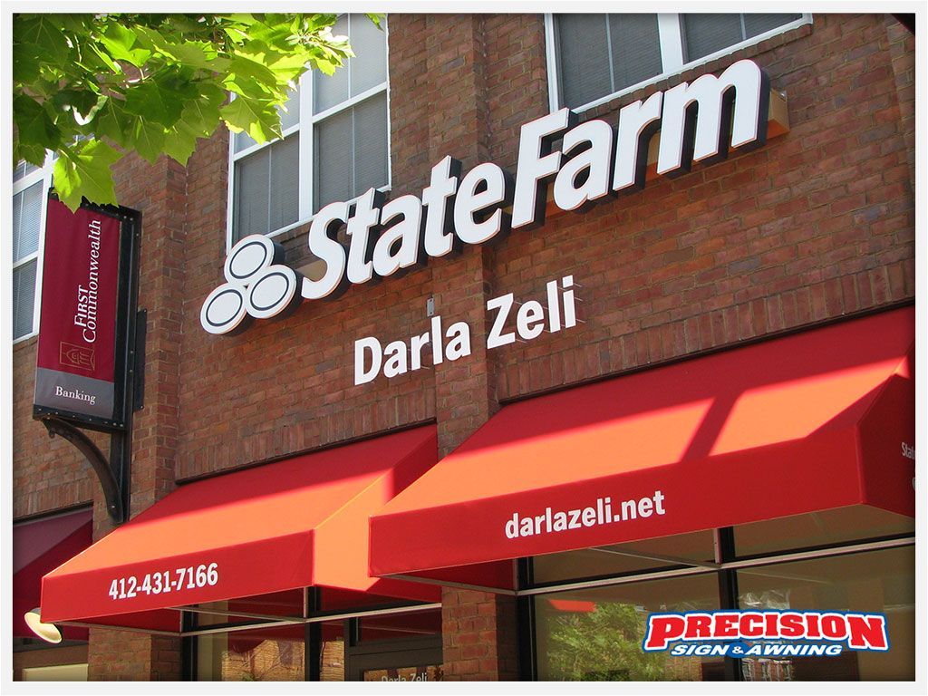 State Farm office with red awnings and sign on brick building.
