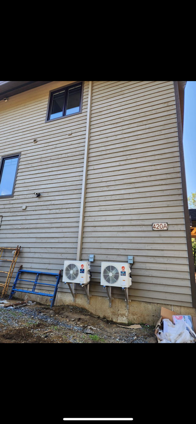 Côté d'une maison avec deux unités de climatisation fixées au mur.