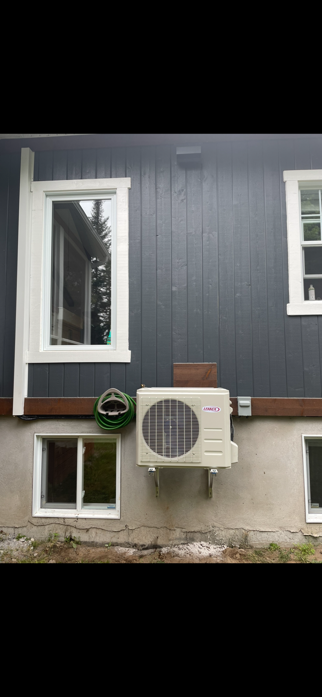 Mur extérieur avec une fenêtre, un climatiseur et de petites fenêtres au sous-sol.
