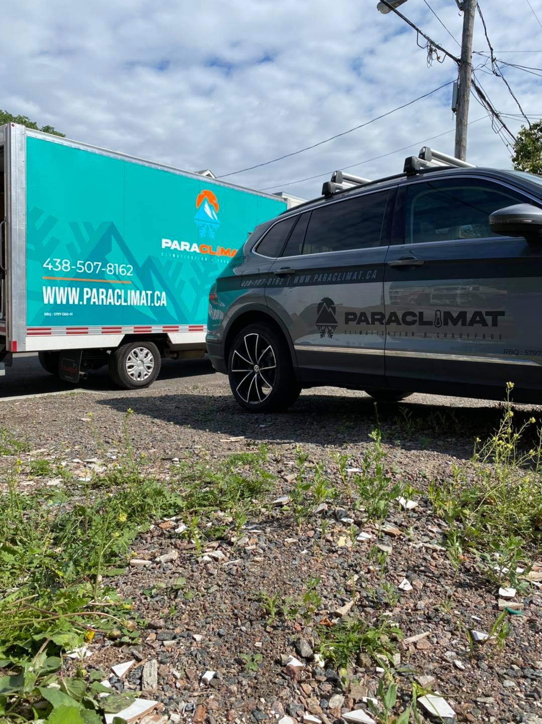 Camion et SUV arborant la marque « Paraclimat », de couleur turquoise et grise, stationnés sur un terrain en terre avec de la végétation.
